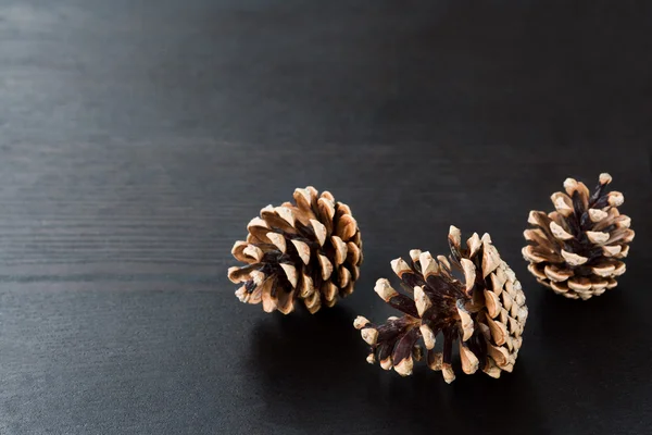 Cones de pinho em fundo de madeira preta — Fotografia de Stock