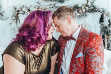 LGBTQ lezbiyen çifti Noel 'i veya yeni yılı birlikte kutluyorlar. Eşcinsel kadın ve erkek partneri evdeki kanepede sarılıyorlar. Kış tatili ruhu. Birbirine aşık çift