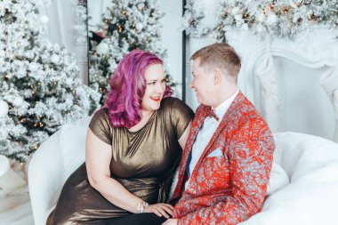 LGBTQ lezbiyen çifti Noel 'i veya yeni yılı birlikte kutluyorlar. Eşcinsel kadın ve erkek partneri evdeki kanepede sarılıyorlar. Kış tatili ruhu. Birbirine aşık çift