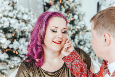 LGBTQ lezbiyen çifti Noel 'i veya yeni yılı birlikte kutluyorlar. Eşcinsel kadın ve erkek partneri evdeki kanepede sarılıyorlar. Kış tatili ruhu. Birbirine aşık çift.