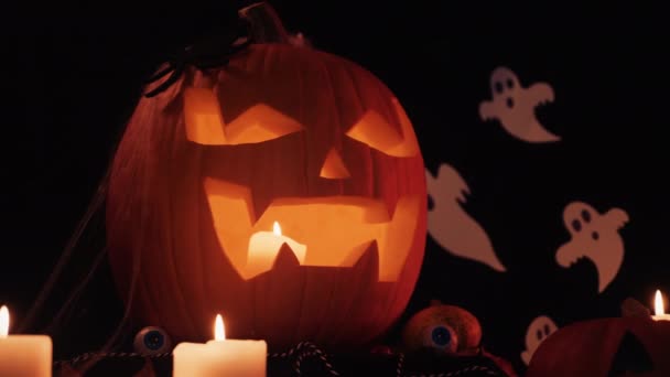Halloween dekoratinok az asztalon. Halloweeni tökfej. Hagyományos finomságok. Nagy Rémült Tökfej Közelkép. Ragyogó tök. — Stock videók