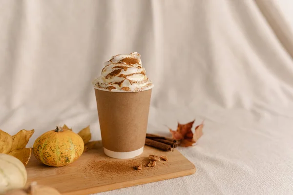 Coffee Take Away Cup in Autumn Pumpkin Set Up. Pumpkin spice latte with whipped cream and fresh cinnamon. Coffee to go with Cream and Cinnamon on Top. Autumn Latte Cinnamon