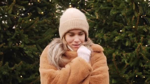 Симпатичная девушка, улыбающаяся зимой в лесу, чувствует холод. Любимый видеопортрет девушки — стоковое видео