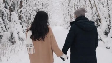 Kışın ormanda el ele tutuşan sevimli bir çift. Geçmişe Bakış 'tan Aşk Hikayesi