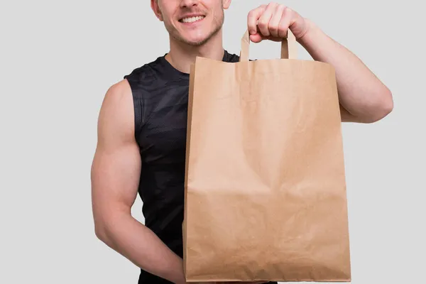 Sportman håller matsäck. Man med papperspåse i händerna. Hälsosam mat, hälsosam mat, Sport Concept. Närbild — Stockfoto