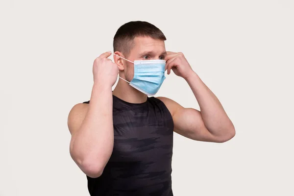 Sportman zet medisch masker op geïsoleerd. Een man met een medisch masker. Medische Masker in handen. Gezondheidsbescherming, Sportsa Concept — Stockfoto