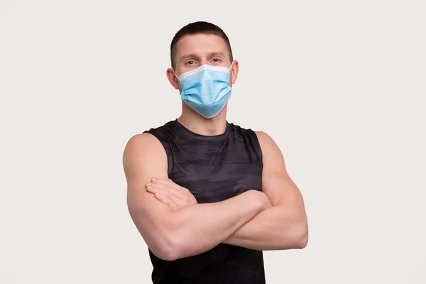 Sportsman bär medicinsk mask. Man händer korsade med mask. Hälsosamt liv, medicinskt skydd, sport koncept. Idrott — Stockfoto
