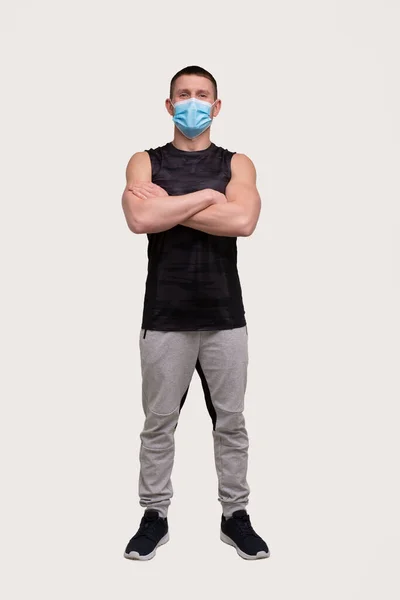 Sportman draagt een medisch masker. Man Handen gekruist met Masker. Gezond leven, Medische bescherming, Sport Concept. Man in volle lengte — Stockfoto