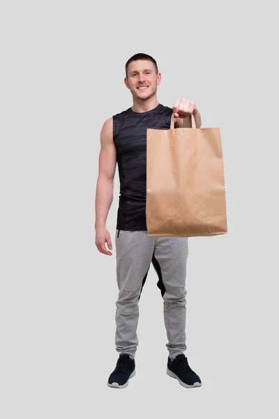 Sac alimentaire Sportman Holding. Homme avec sac en papier dans les mains. Healthy Eating, Healthy Food, Sport Concept. Homme debout pleine longueur — Photo