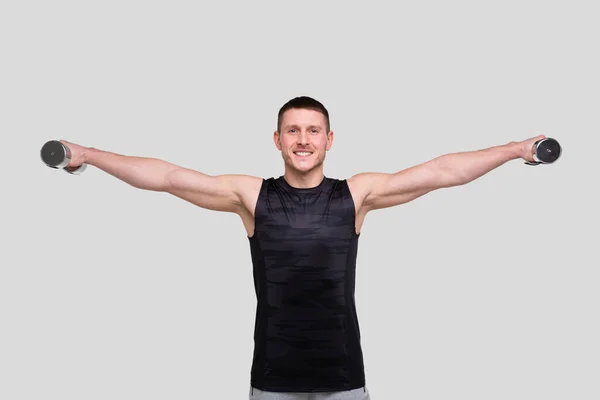 Mann pumpt mit Hantel-Händen zur Seite. Sprinter beim Traning der Bizeps-Muskeln. Fitnessraum, Hebesportkonzept. — Stockfoto
