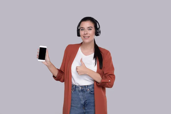 Girl Listening to Music from Phone Mostrando o polegar para cima. Menina apontando para tela verde do telefone. Isolados — Fotografia de Stock
