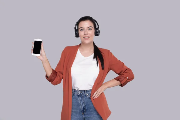 Flicka lyssnar på musik från telefon visar enheten. Flickvännen håller i telefonen. Isolerad — Stockfoto