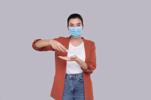 Flicka bär medicinsk mask med hjälp av handdesinfektionsmedel. Flicka med händerna antiseptisk isolerad — Stockfoto