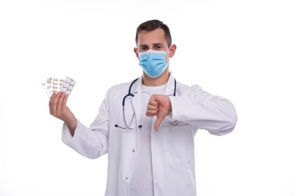 Άνθρωπος Γιατρός Εμφάνιση Χάπια και Αντίχειρας κάτω φορώντας ιατρική μάσκα. Doctor Holding δισκία. Γιατρός άνθρωπος απομονωμένος. — Φωτογραφία Αρχείου