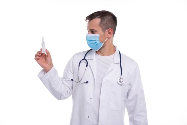 Doctor sosteniendo la nariz aerosol aislado. Hombre médico con aerosol nasal en las manos con máscara médica —  Fotos de Stock