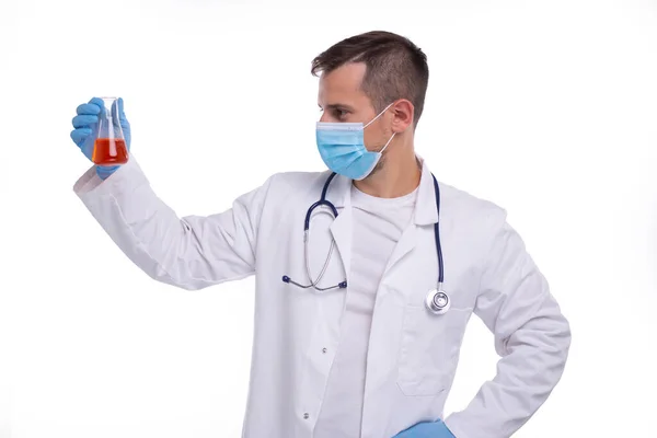 Man Doctor Examing Flask med Colorfull Liquid Wearing Medical Mask Isolerad. Medicin, vetenskapsbegrepp — Stockfoto
