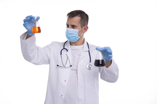 Masculino Doctor Examing Flask com Colorfull líquido vestindo máscara médica, luvas isoladas. Ciência, Medicina, Conceito de Vírus. Homem Doutor Smilling. — Fotografia de Stock