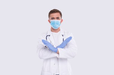 Erkek doktor elleri çapraz dur işareti takılı tıbbi maske ve eldivenler. İzole Eller İmzası
