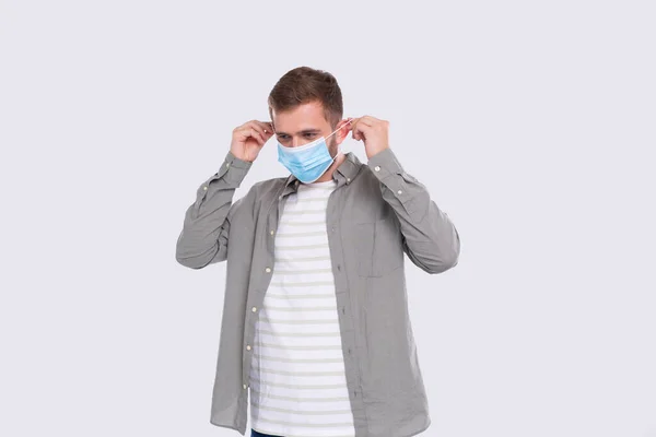 Man sätter på medicinsk mask isolerad. Man i grön tröja visar hur man tar på sig medicinsk mask. Hälsa, virus, medicinskt koncept. Handledning — Stockfoto