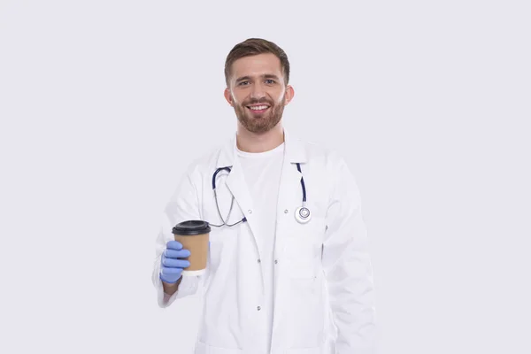 Man Doctor Holding Coffee Take Away Cup Χαμογελώντας φορώντας γάντια απομονώνονται. Γιατρός κρατώντας καφέ για να πάει Κύπελλο. Πιες. — Φωτογραφία Αρχείου