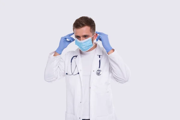 Man Doctor zet op Medical Mask dragen handschoenen. Dokter medische werkkleding. Medisch concept. Artsen met een medisch masker — Stockfoto