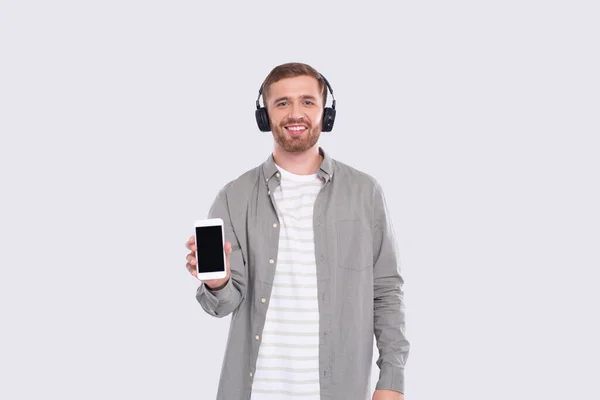 Чоловік слухає музику з пристрою, що показує телефон. Чоловік тримає телефон. Ізольовані — стокове фото