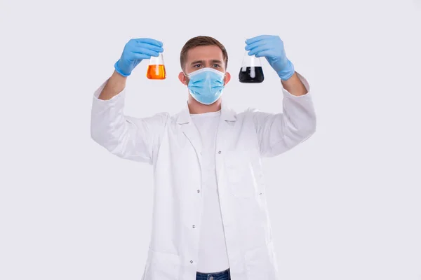 Männliche Doktor Prüfkolben mit farbenfroher Flüssigkeit tragen medizinische Maske, Handschuhe isoliert. Wissenschaft, Medizin, Viruskonzept. Der Mann lächelt. Flüssigkeit — Stockfoto