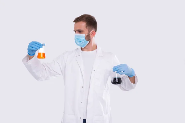 Чоловік Доктор Видалення Фласка з кольоровою рідиною в медичній масці, рукавички ізольовані. Наука, медицина, концепція вірусу. Чоловік Доктор Усміхається. Рідина — стокове фото