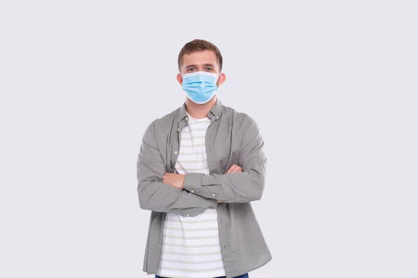 Uomo che indossa maschera medica mani incrociate isolate. Uomo in camicia verde con maschera medica. Salute, Virus, Concetto medico — Foto Stock