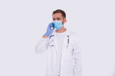 Doktor telefonda konuşuyor. Tıbbî maske ve eldiven takıyor. Ticari, Alışveriş, Reklam Konsepti. Teknoloji