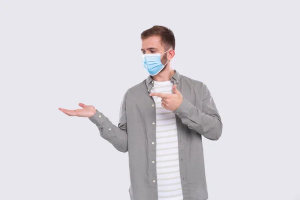 Man visar hand till sida pekar på det tittar på det. Man bär medicinsk mask. Gesture Concept Isolerad — Stockfoto