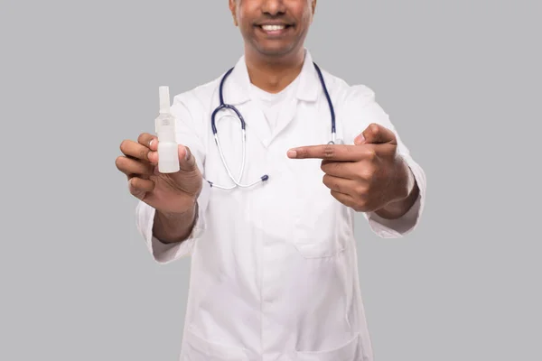 Doctor apuntando a la nariz aerosol primer plano aislado. Médico indio con spray nasal en las manos —  Fotos de Stock