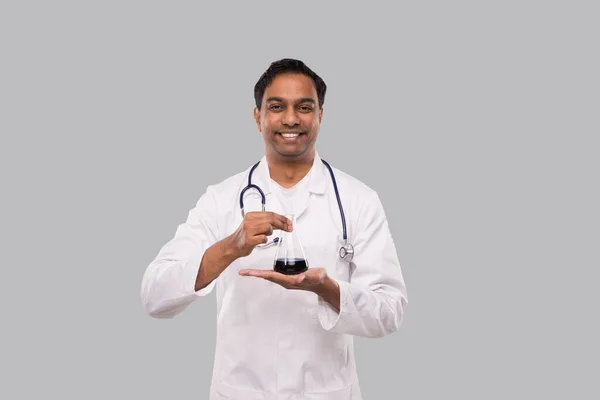 Mężczyzna-lekarz pokazuje Flask z odizolowanym płynem Colorfull. Nauka, medycyna, koncepcja wirusa. Indianin lekarz uśmiech. — Zdjęcie stockowe