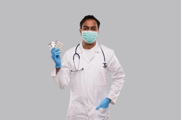 Man Doctor visar piller bär medicinsk mask och handskar. Läkare som håller i tabletter. Indiska Man Doctor Isolerad. — Stockfoto