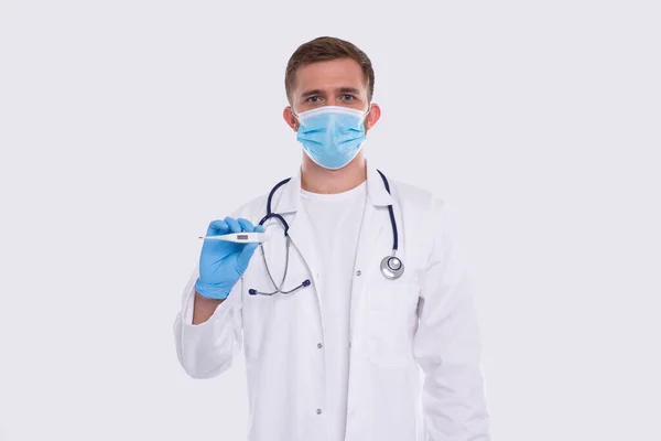 Doutor mostrando termômetro vestindo máscara médica e luvas isoladas. Homem Doutor com Termômetro em Mãos. Vida saudável, Doutor, Conceito de vírus — Fotografia de Stock