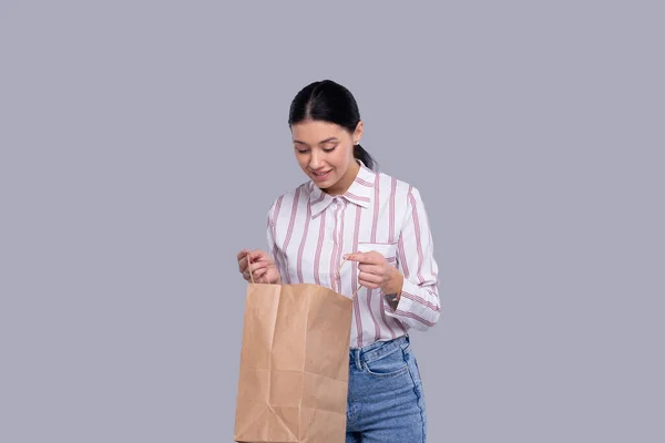Дівчина дивиться в торгову сумку. Дівчина купує. Концепція покупок Ізольовані — стокове фото