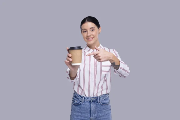 Girl Apinting at Coffee Take Away Cup. Chica con para ir taza de café en manos aisladas Imagen de stock
