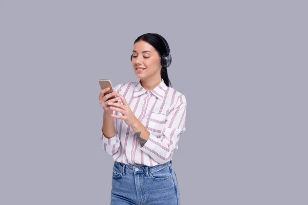 Flicka lyssnar på musik från telefonen njuter av det. Flicka lyssnande musik med trådlösa hörlurar Isolerad — Stockfoto