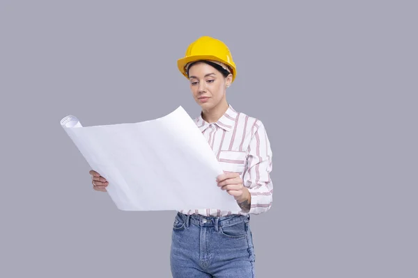 Girl Construction Worker Holding House Plan in Hands Watching at It. Girl Architect Holding Blueprints. Yellow Hard Helmet. Worker — Foto Stock