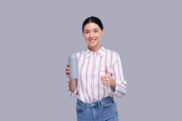 Chica sosteniendo lata puede mostrar el pulgar hacia arriba. Chica con la botella de cerveza en las manos. Bebida alcohólica puede aislado Imagen de archivo