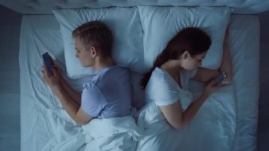Yatakta Telefonu Kullanan Çift. Yatakta Telefonla Konuşan Çift. İnternetten Alışveriş Eğlencesi. Yatakta bir çift. Arkadaşlar, Çiftler, Aşıklar Konsepti.
