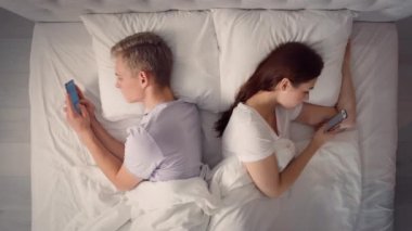 Yatakta Telefonu Kullanan Çift. Yatakta Telefonla Konuşan Çift. İnternetten Alışveriş Eğlencesi. Yatakta bir çift. Arkadaşlar, Çiftler, Aşıklar Konsepti.