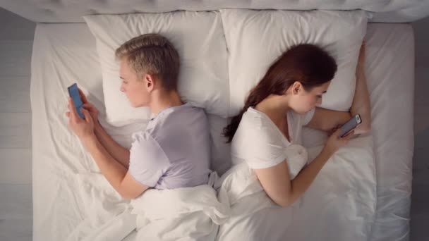夫妻在床上用手机 夫妻在床上用电话聊天 网上购物的乐趣 一对夫妇在床上 情人概念 — 图库视频影像