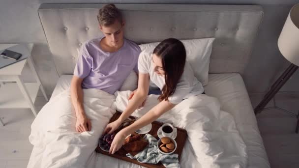 夫妻在床上吃早餐 早上早餐 女孩用葡萄喂男人 — 图库视频影像