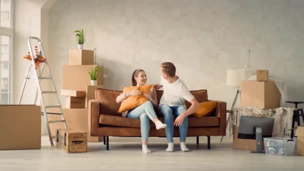 一对年轻夫妇在新家的沙发上 夫妻谈新家 在索法的家庭安乐窝松驰 — 图库视频影像