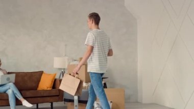 Evde yemek yiyen bir çift. Adam eve fast food ve kahve getiriyor, Kız evde çalışıyor. Çift Yeni Eve Taşındı ve Kahveyle Akşam Yemeği Yiyor.