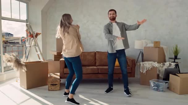 新しい家で踊るカップル カップルは新しいフラットダンスの幸せに移動しました 初めての家庭購入を祝うカップル — ストック動画