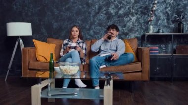 Evde oyun oynayan ve bira içen bir çift olarak mı? Evde Ellerinde Gamepad 'le oyunlar oynayan çift. Evdeki Oyuncular.