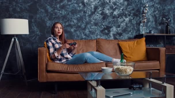女孩在玩控制台游戏 一个人呆在家里放松与啤酒和游戏在家里 检疫时间 — 图库视频影像