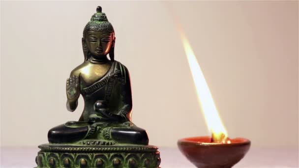 Statuette of Buddha and a burning candle. — Stock Video